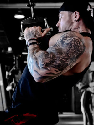 Black muscle-fit sleeveless tank top with a crew neck, worn by a man with extensive arm tattoos.