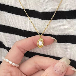 Gold pearl necklace with sterling silver chain and oval pendant.
