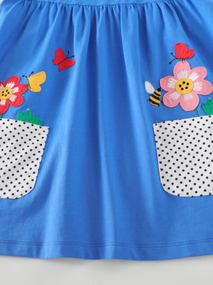 Blue cotton dress with bird and flower appliques and polka dot pockets.