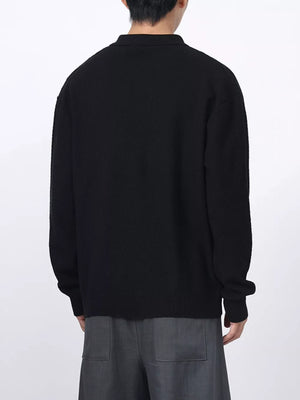 Men's black textured knit polo shirt with long sleeves.
