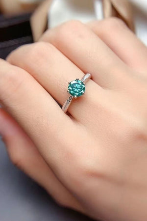 Teal moissanite solitaire ring with pave band on finger