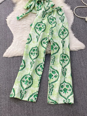 Green tropical print polyester two-piece set with wide-leg pants and belted detail.