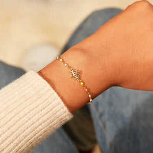 Gold enamel lotus bead bracelet with colorful accents on a wrist.