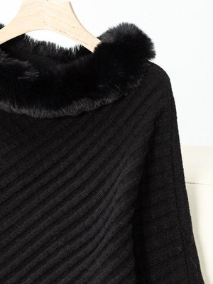 Black knit poncho with diagonal ribbing and faux fur trim detail.