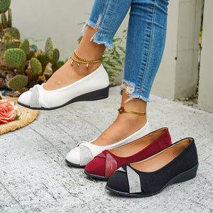 Rhinestone adorned slip-on wedge flats in red, beige, and black with textured fabric and bow detail.