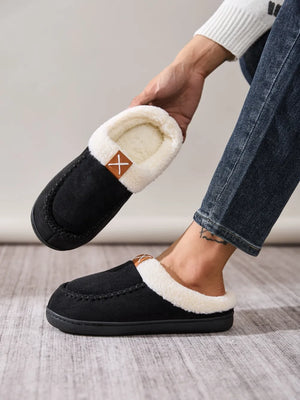 Black suede shearling-lined moccasin slides with a decorative stitch and brown logo tag.