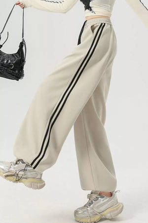 Beige wide-leg sweatpants with black side stripes and drawstring waist.