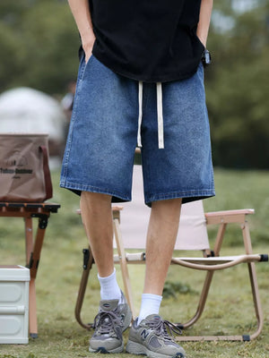 Relaxed fit blue denim shorts with white drawstring, mid-thigh length.