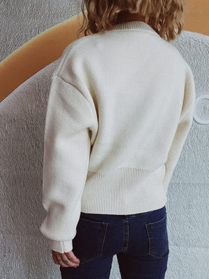 White ribbed hemline zip-front knit top with crew neck and long sleeves.