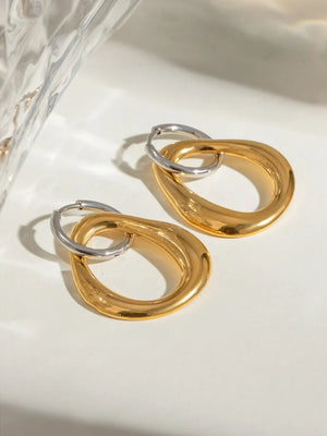 Two-tone sculptural asymmetric hoop earrings in gold and silver tones.