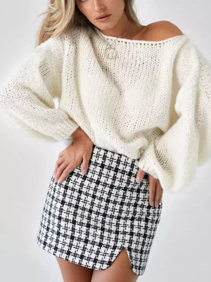 Cream oversized knit sweater with balloon sleeves and boat neck, styled with a plaid skirt.