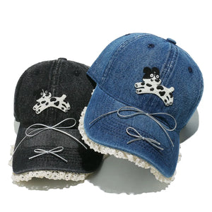 Denim baseball cap with puppy appliqué, lace trim, and bow details.