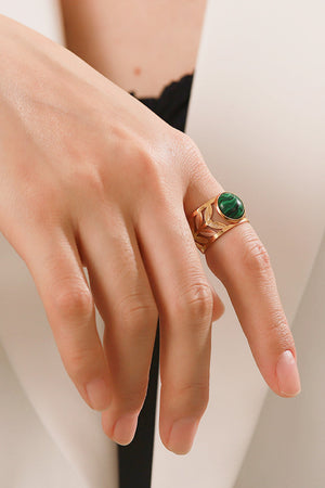 Gold ring with leaf-cut detail and a malachite stone on a finger.