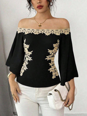 Black off-shoulder blouse with bell sleeves and gold floral embroidery detail.