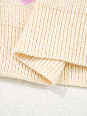 Cream knit sweater with pink heart pattern detail and ribbed cuffs.
