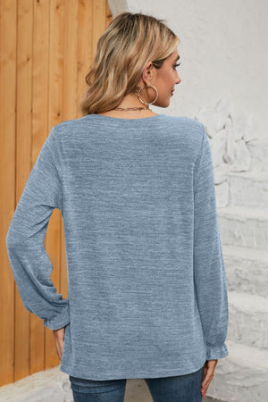 Light blue knit top with ruffled cuffs and long sleeves.