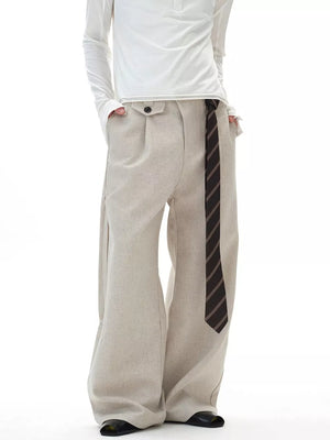 Men's beige wide-leg cargo pants with button closure and a striped tie accent.