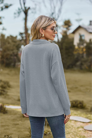 Textured cable knit polo top in light blue with a collared neckline and long sleeves.