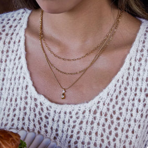 Gold layered pendant necklace with delicate chains and a small drop charm with two stones.