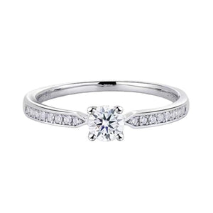 Sterling silver ring with a round moissanite center stone and channel-set accent stones.