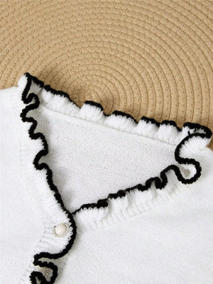 White knit sweater with ruffled V-neck trim and pearl button detail.