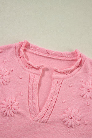 Blush pink knit sweater with embroidered floral details and notch neck.