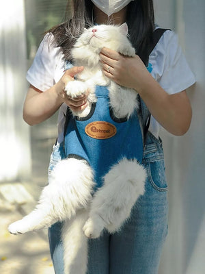 Blue denim-like pet carrier backpack with adjustable straps, holding a white cat.
