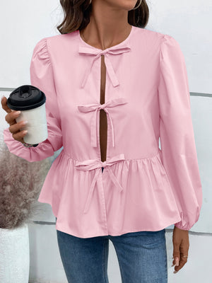 Blush pink peplum blouse with keyhole neckline and bow details.