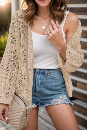 Open-knit crochet cardigan in Dust Storm with wide sleeves, worn over a white tank top and denim shorts.