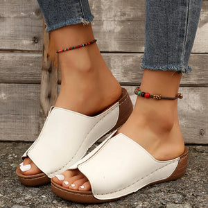 White stitched edge wedge mules with peep toe and wooden heel detail.