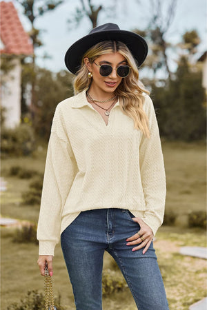 Ivory textured cable knit polo top with V-neck and long sleeves.