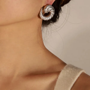 Silver sculptural swirl stud earrings with a twisted texture.