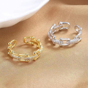 Open chain-link ring with zircon accents in gold color and white gold.