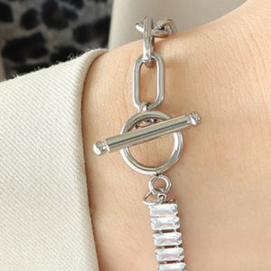 Silver chain-link bracelet with toggle clasp and baguette zirconia charms.