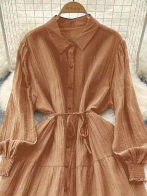 Caramel textured tiered long sleeve button-down dress with cinched waist and smocked cuffs.