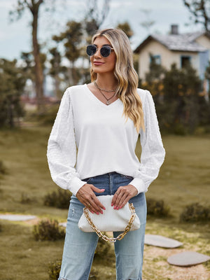 White v-neck blouse with Swiss dot puff sleeves and a relaxed fit.