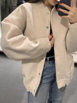 Beige boucle cocoon jacket with snap closure and pockets.
