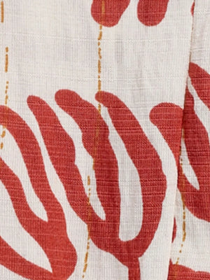 Maxi dress fabric detail with red abstract floral print and thin gold dash lines on white textured material.