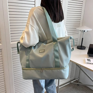 Dual-compartment travel tote in Dusty Blue with metallic trim and green straps.