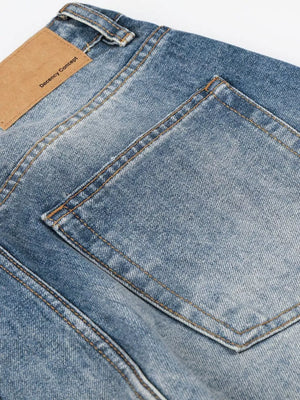 Men's blue wide leg vintage wash jeans with tan leather patch detail.