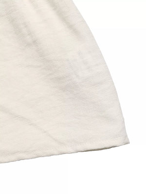 Beige textured fabric detail of a chic tie-front two-piece ensemble.