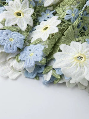 Embroidered maxi dress detail with white and blue floral appliqué and green leaves.