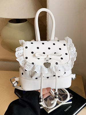 Charming polka dot lace mini backpack in cream white with bow detail and heart charm.
