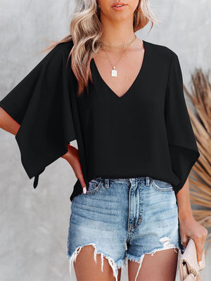 Black V-neck blouse with flutter sleeves, styled with denim shorts.