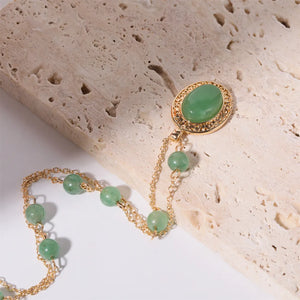 Gold chain necklace with neon green jade orb and beaded accents