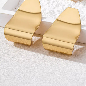 Golden alloy geometric earrings with a bold, sculptural design.