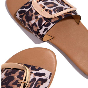 Leopard print slide sandals with gold buckle detail and open toe.