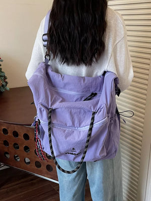 Chic Oxford cloth travel duffel bag in lavender with black rope strap and tassel detail.
