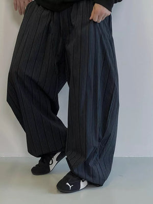 Men's black wide-leg sweatpants with vertical pleats and pockets.