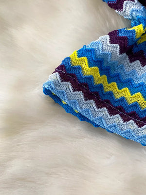 Chevron knit halter crop top in blue, purple, and yellow on white fluffy background.